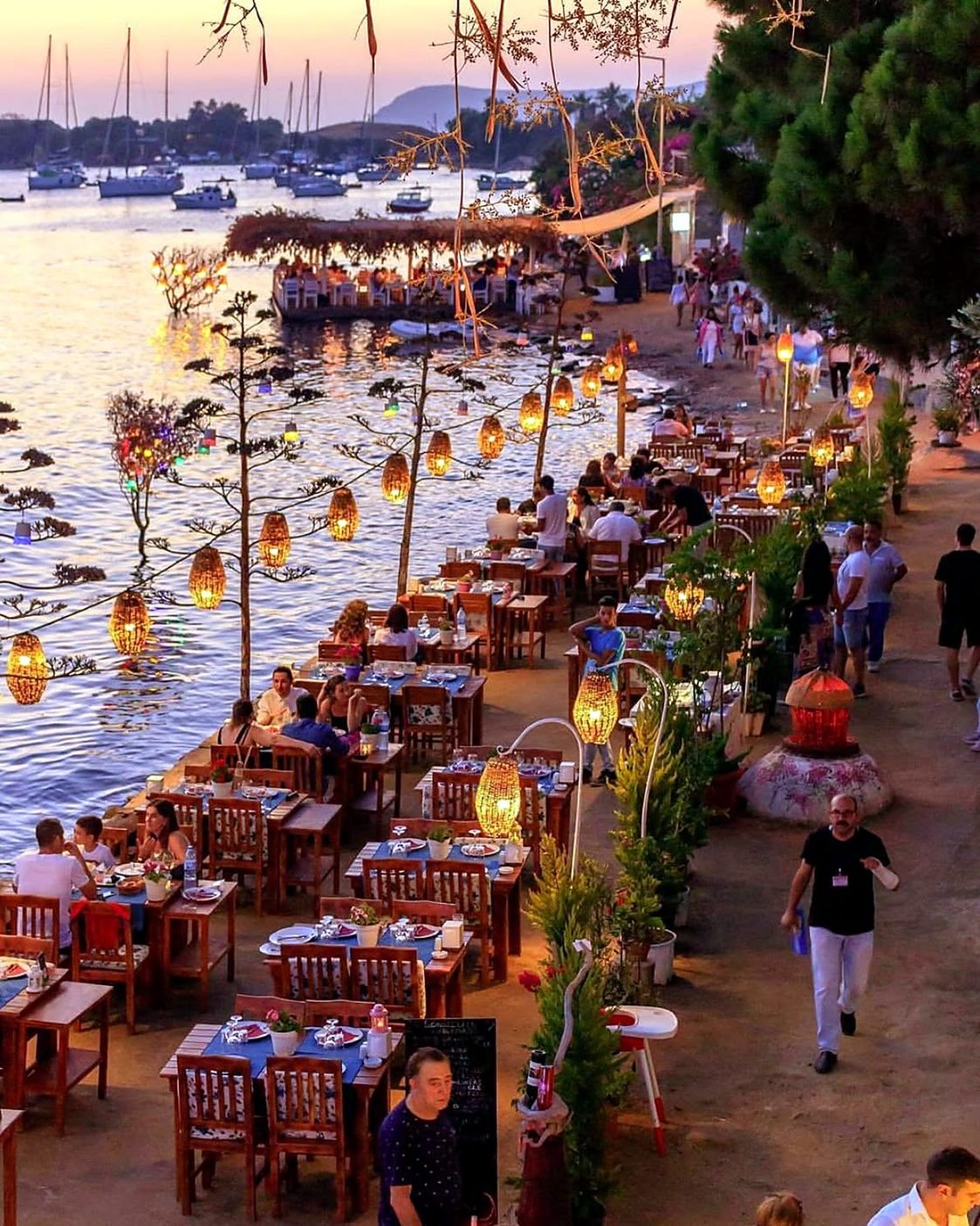 Restaurantes iluminados à beira-mar em Gümüşlük ao pôr do sol