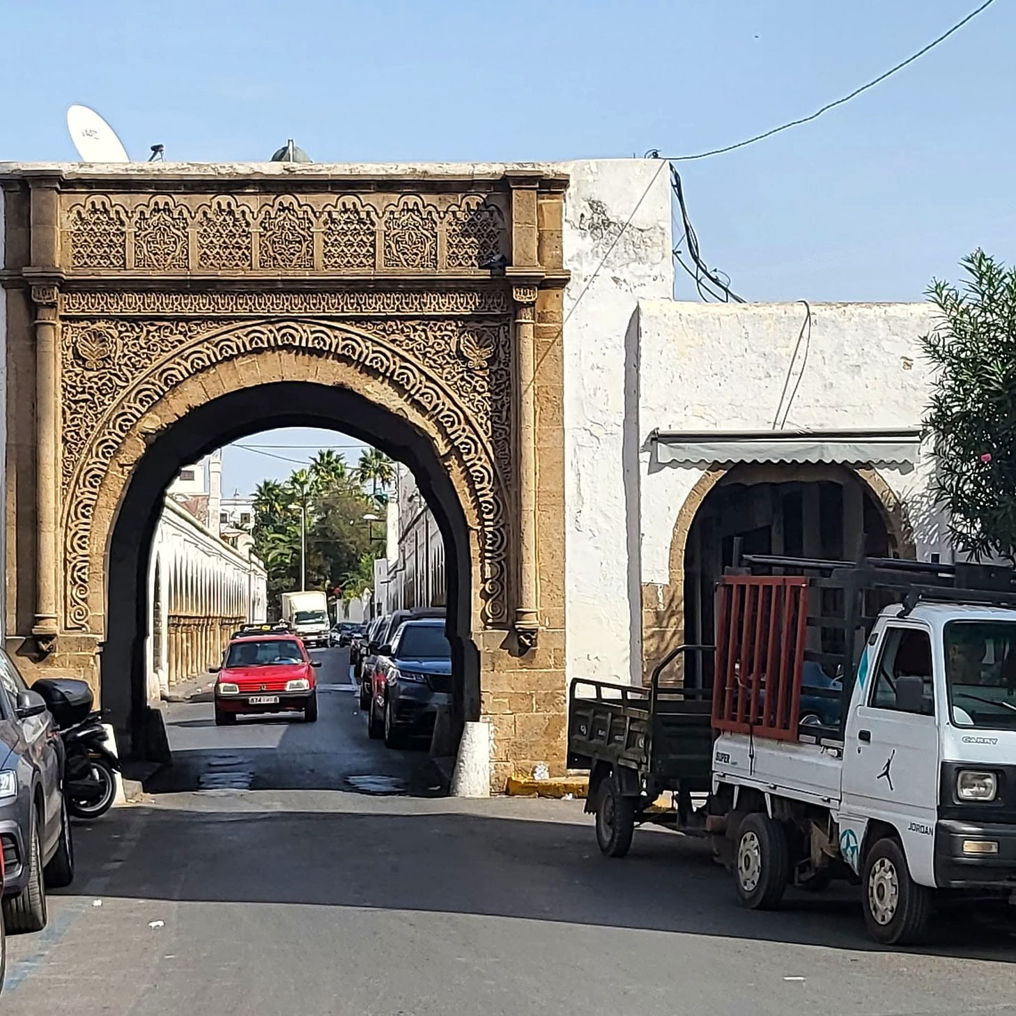 Portal de pedra entalhada no bairro Habous de Casablanca, com carros passando pelo arco