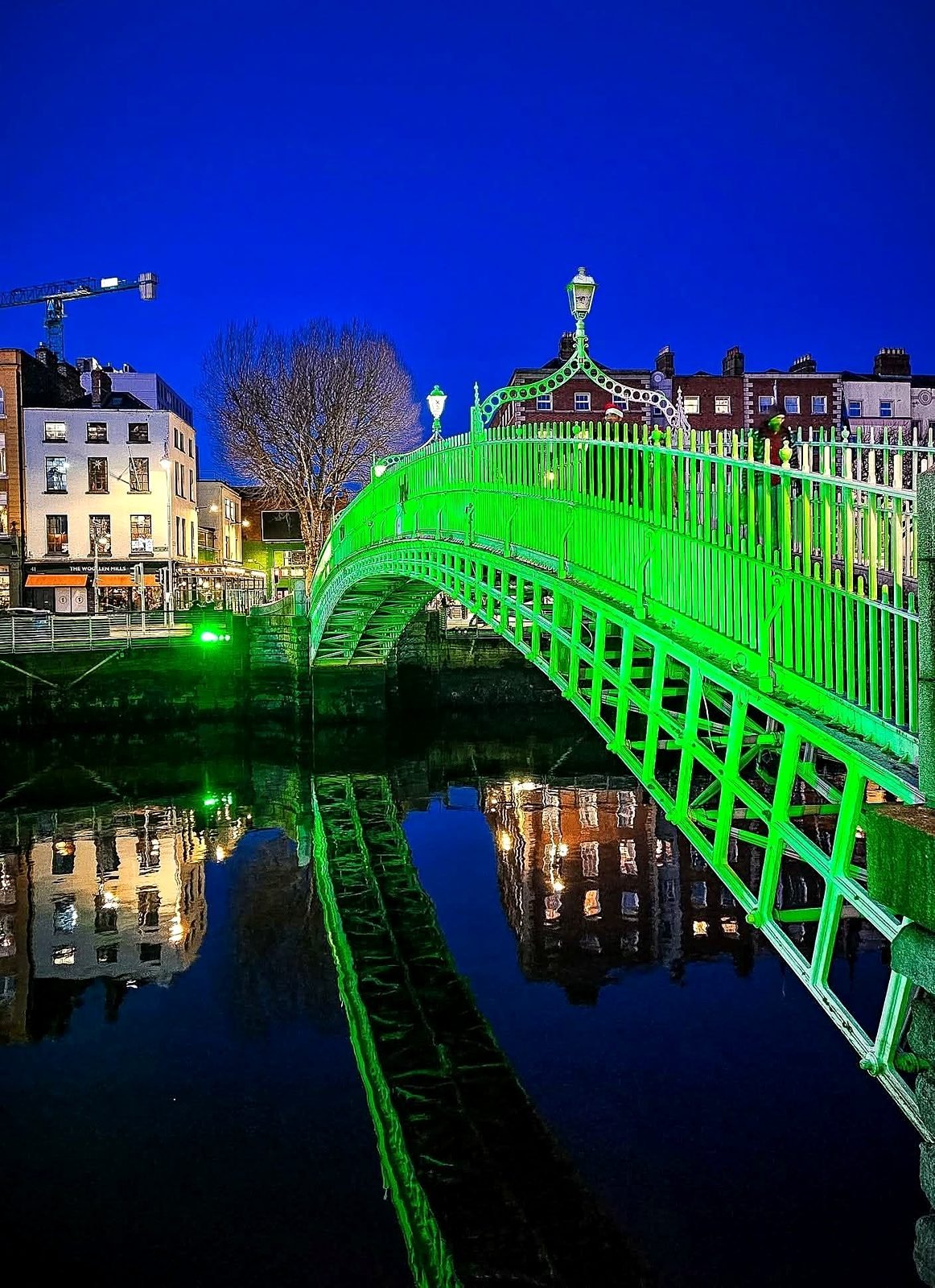 Ha'penny Bridge iluminada de verde sobre o rio Liffey à noite