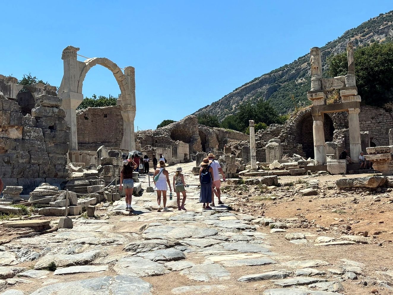 Visitantes caminhando pela via de mármore na parte alta de Éfeso, perto da Fonte de Pólio