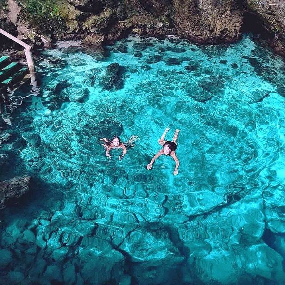Pessoas nadando no cenote Hoyo Azul em Punta Cana, de água azul transparente