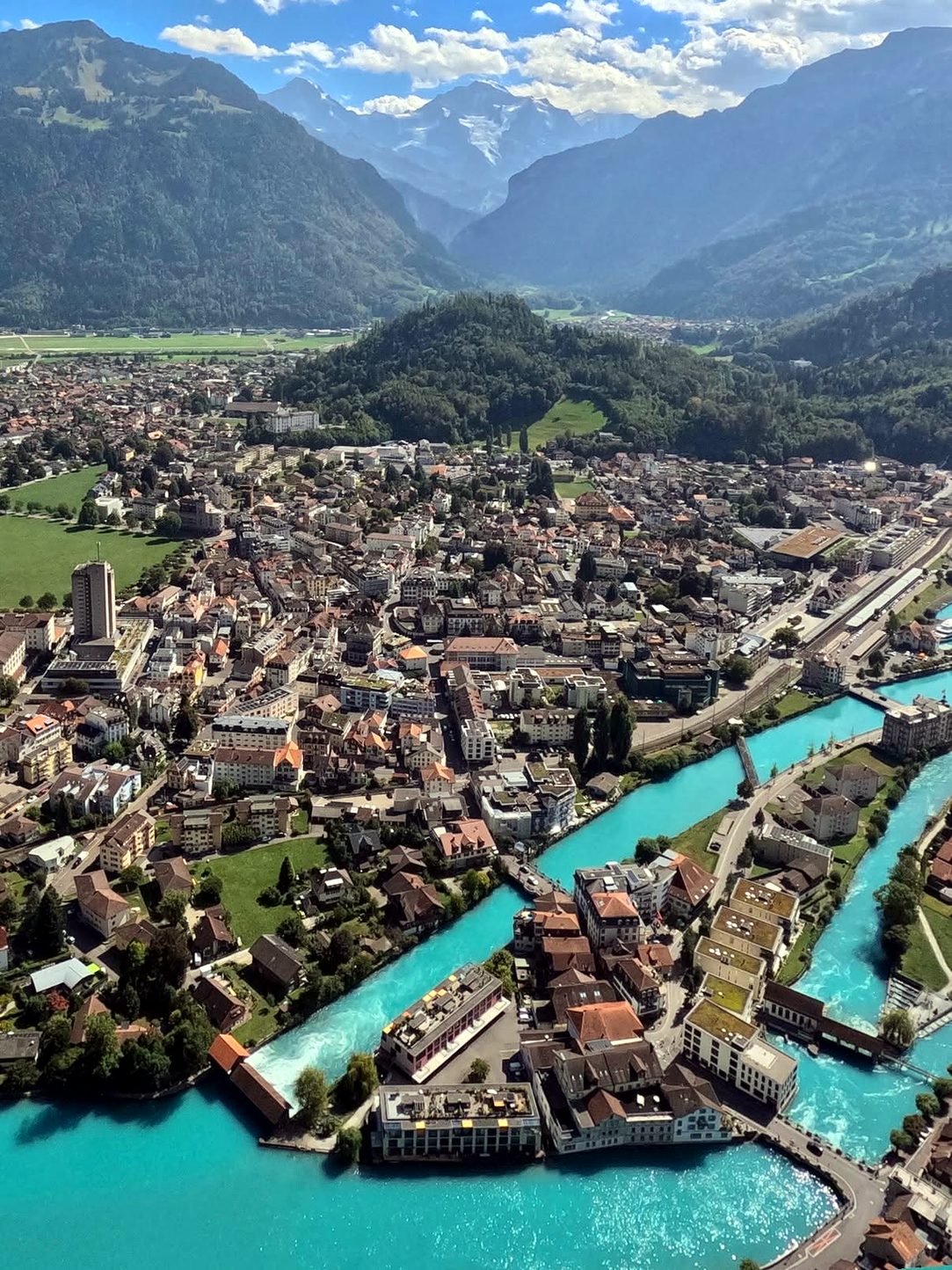 Vista aérea de Interlaken com o rio Aare turquesa entre os lagos e os Alpes ao fundo