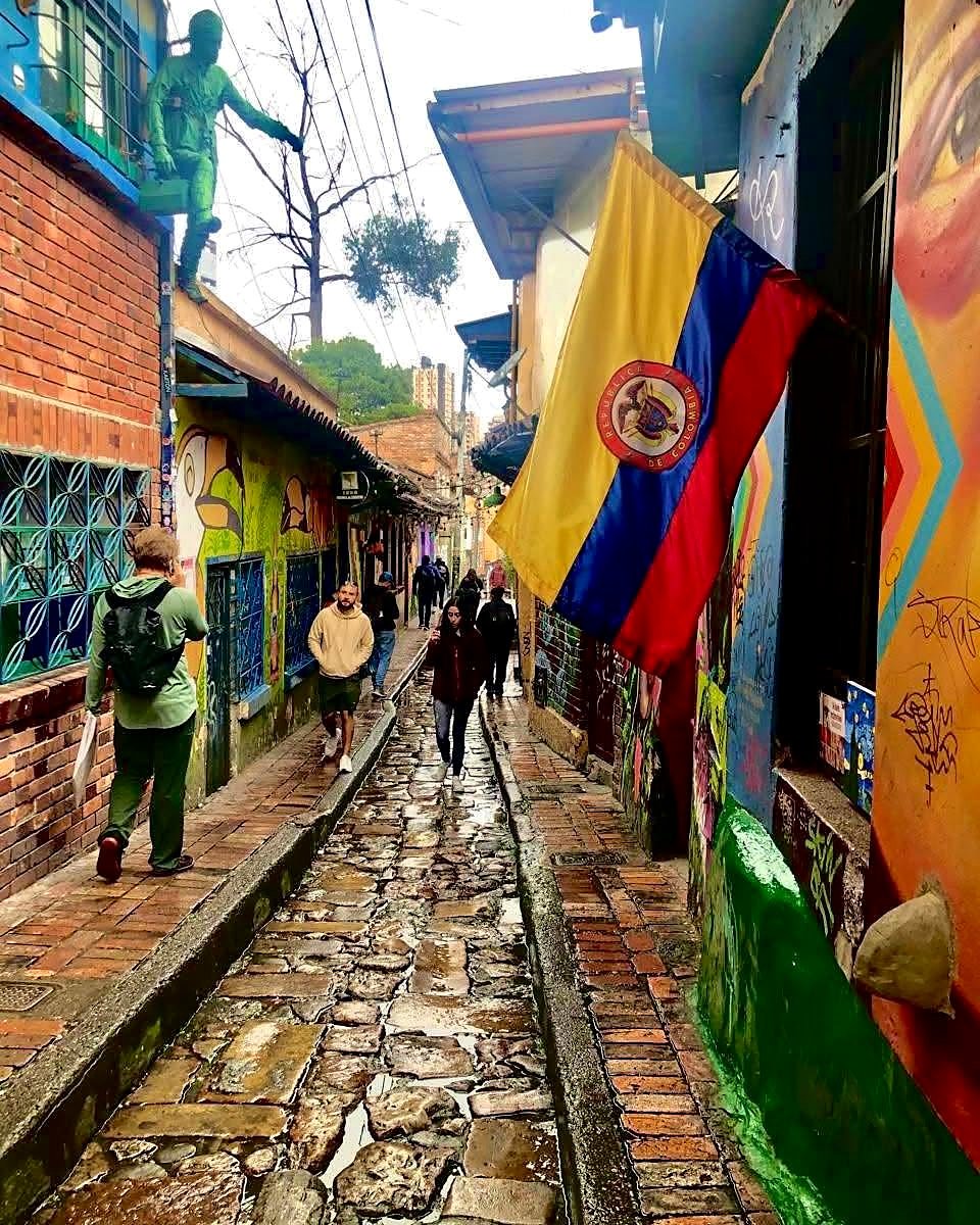 Rua de pedra com grafites e bandeira da Colômbia no bairro La Candelaria