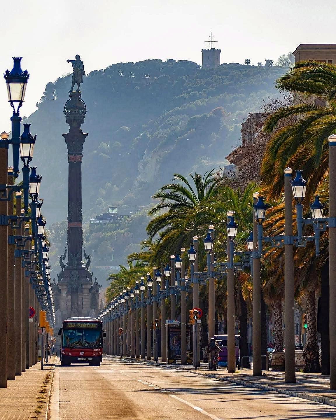 Monumento a Colombo no fim da Rambla em Barcelona, com palmeiras e o morro de Montjuïc ao fundo