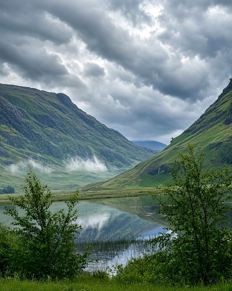 Lago entre montanhas verdes e neblina nas Highlands escocesas