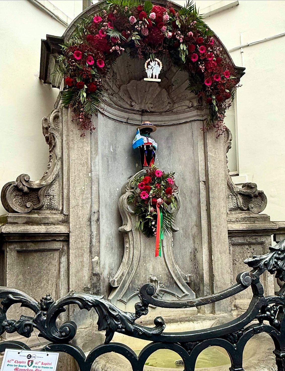 Estátua do Manneken Pis vestida com traje típico e decorada com flores