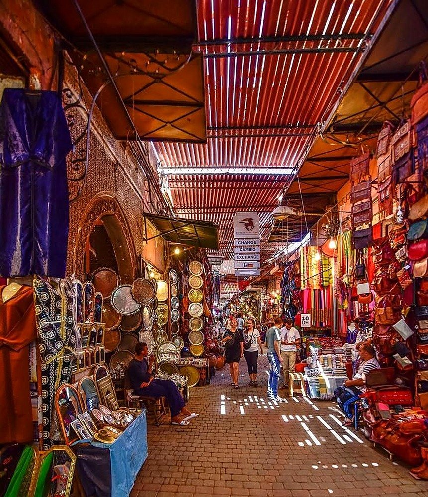 Corredor coberto do souk de Marrakech com luminárias, bolsas de couro e tecidos