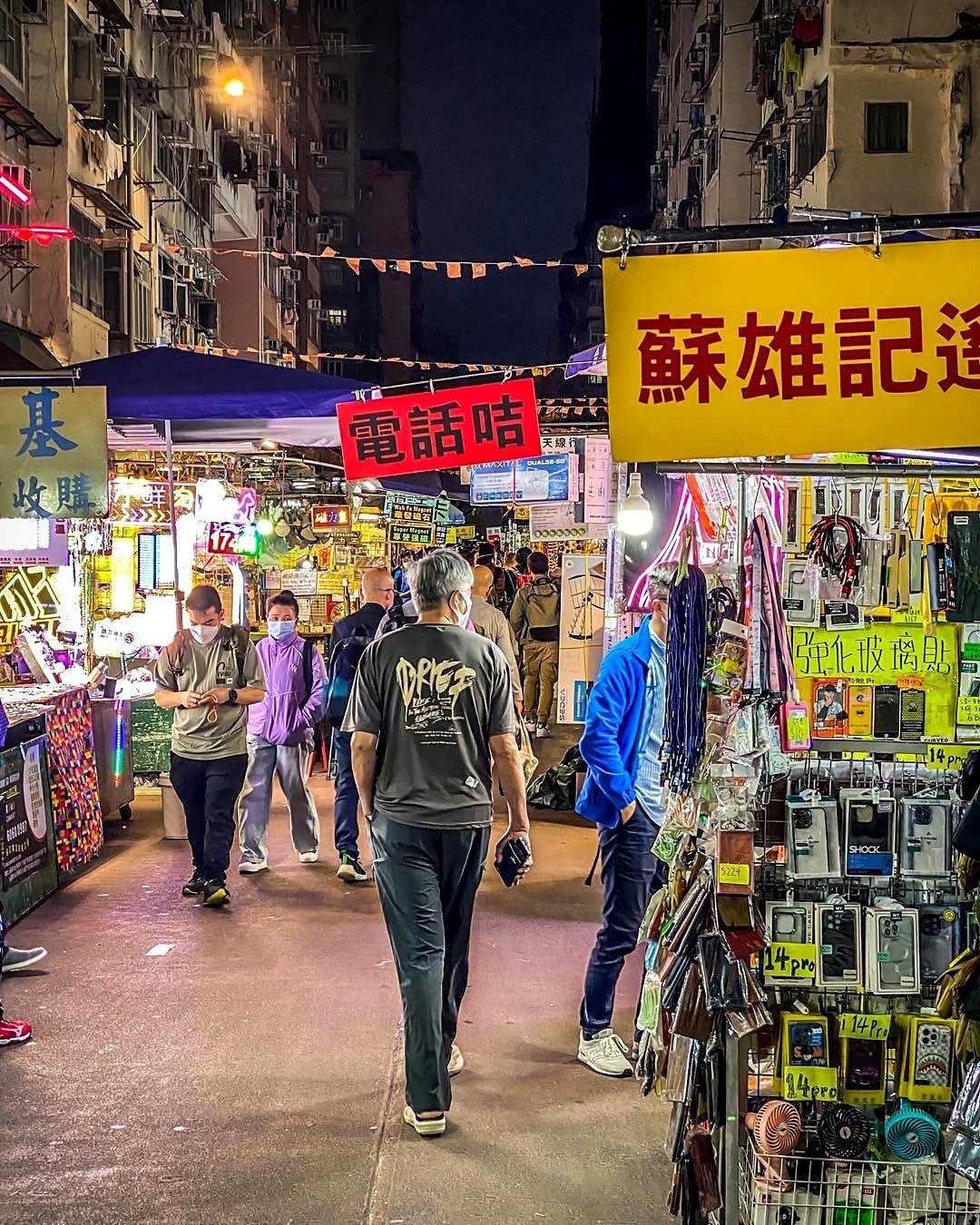 Mercado de rua iluminado com barracas de eletrônicos em Hong Kong