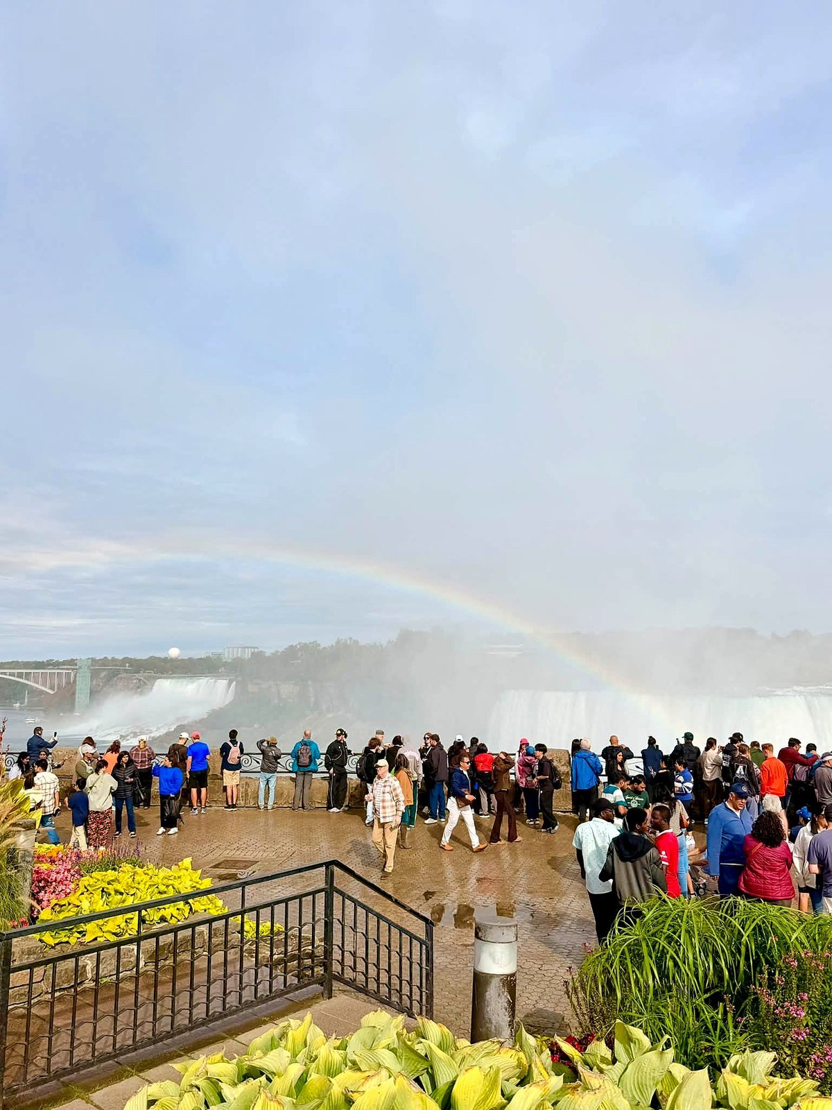 Arco-íris sobre as Cataratas do Niágara, com turistas no mirante