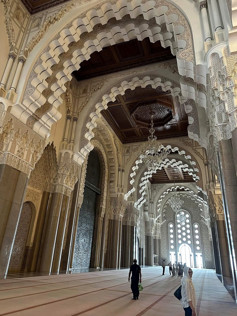Interior da Mesquita Hassan II com arcos de estuque esculpido, teto de cedro e lustres