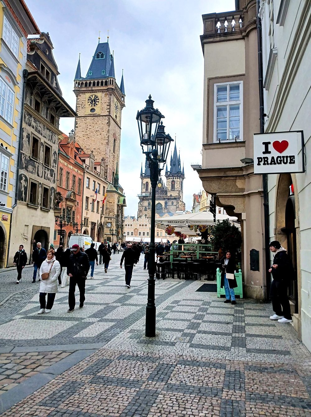 Rua de pedra que leva à Praça da Cidade Velha com a torre da prefeitura e a Igreja de Týn