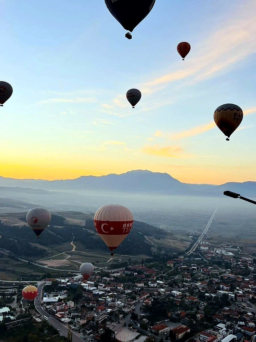 Balões ao nascer do sol sobre o vilarejo de Pamukkale