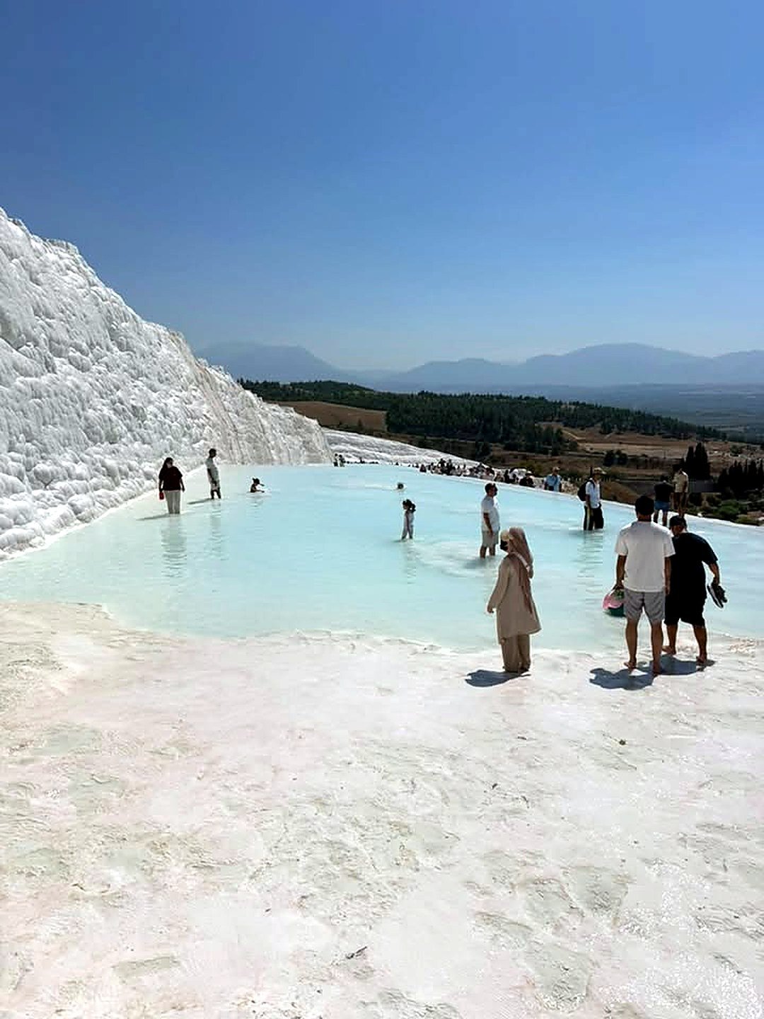 Visitantes caminhando descalços na piscina de travertino de Pamukkale