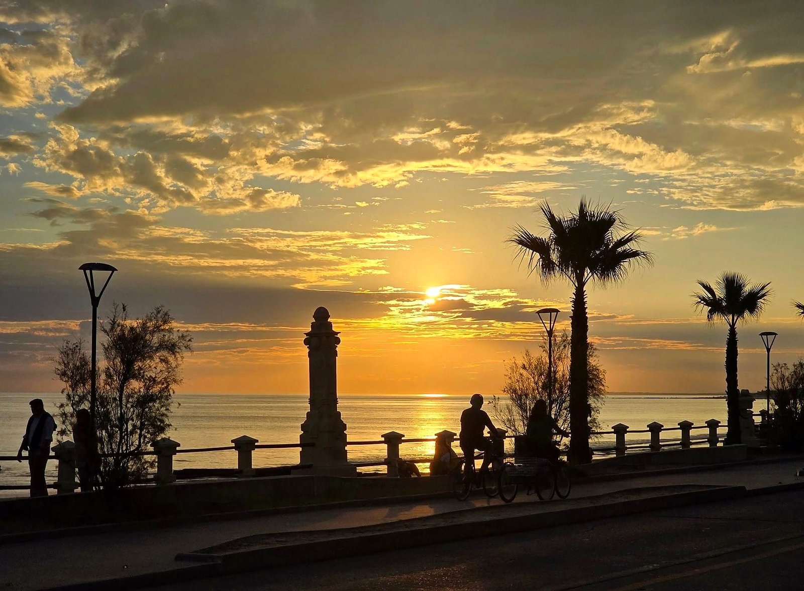 Pôr do sol na rambla de Piriápolis, no Uruguai, com palmeiras
