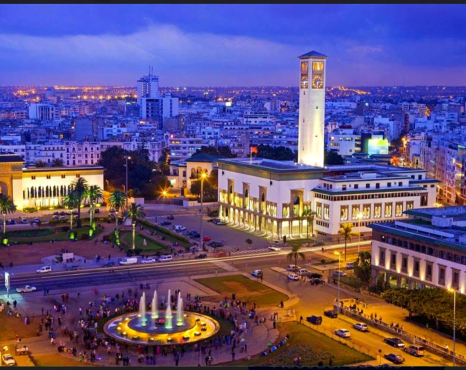 Praça Mohammed V iluminada à noite em Casablanca, com a fonte e a torre do relógio da Wilaya
