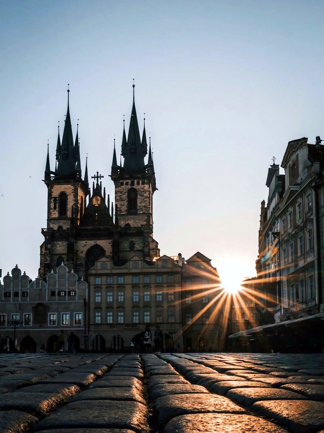 Torres da Igreja de Nossa Senhora diante de Týn ao nascer do sol na Praça da Cidade Velha
