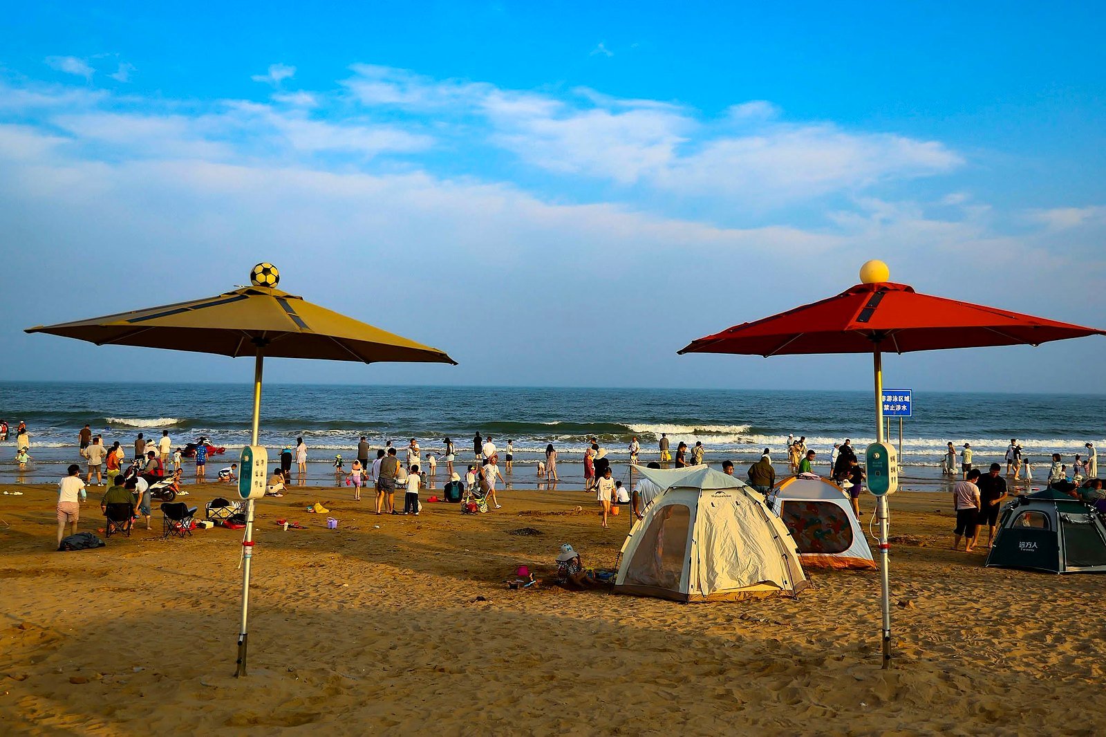 Praia de Qingdao com guarda-sóis e famílias à beira do mar