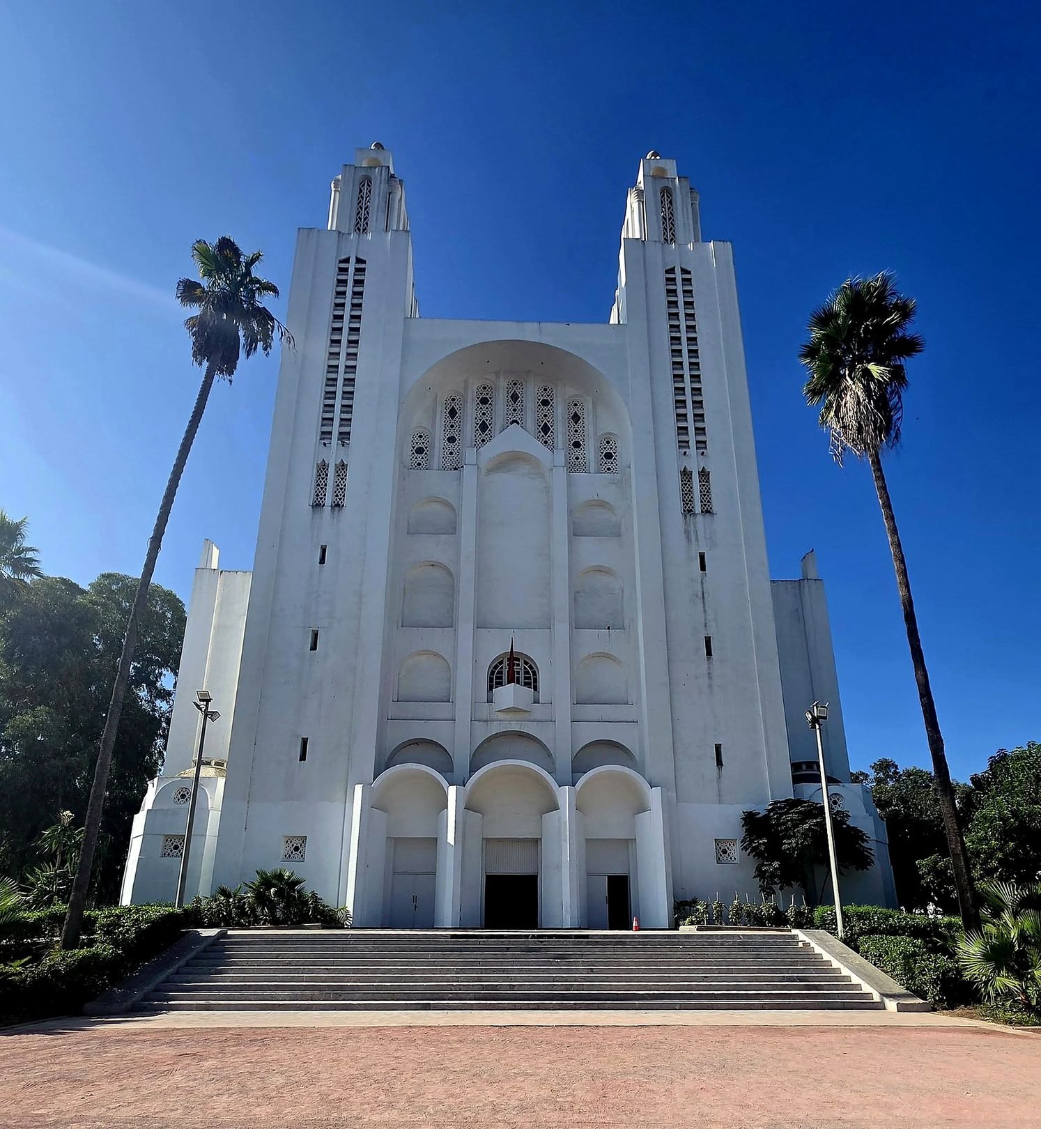 Fachada branca da antiga Catedral do Sagrado Coração em Casablanca, em estilo art déco, entre palmeiras
