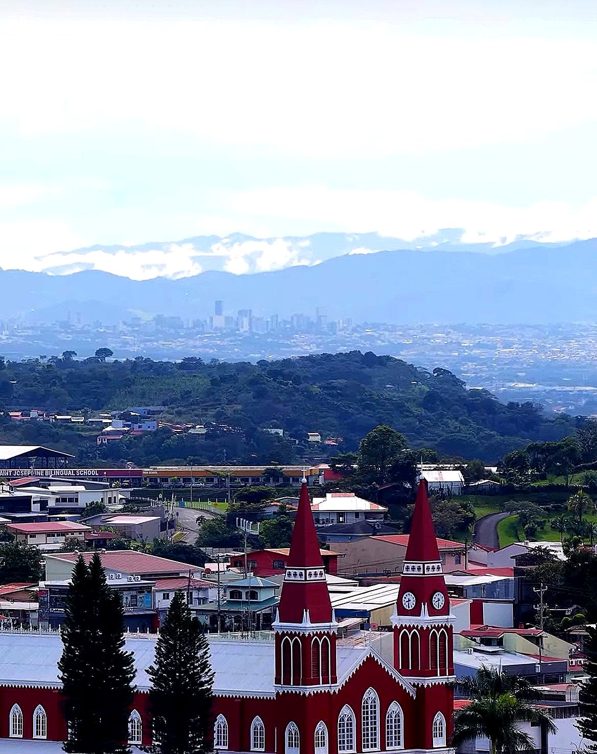 Igreja vermelha de Grecia com a cidade de San José e as montanhas ao fundo