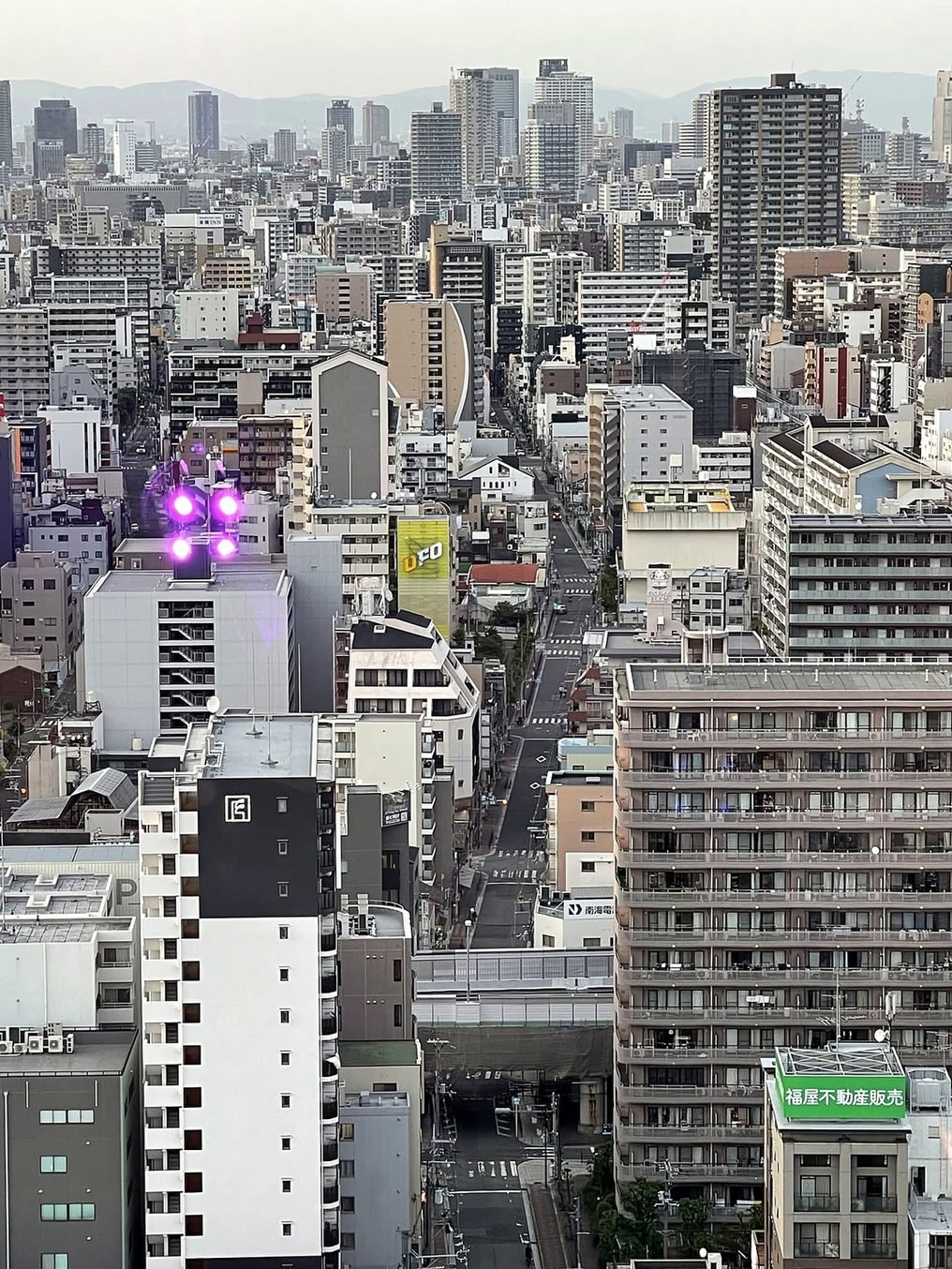 Vista do alto da cidade de Osaka com prédios até as montanhas