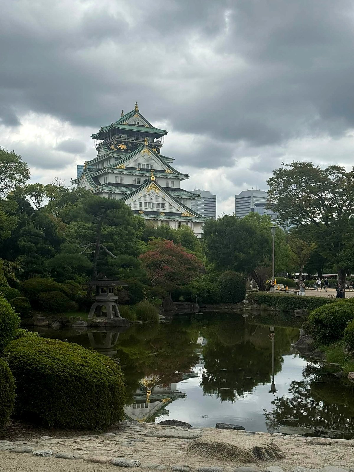 Castelo de Osaka refletido no lago do jardim japonês do parque