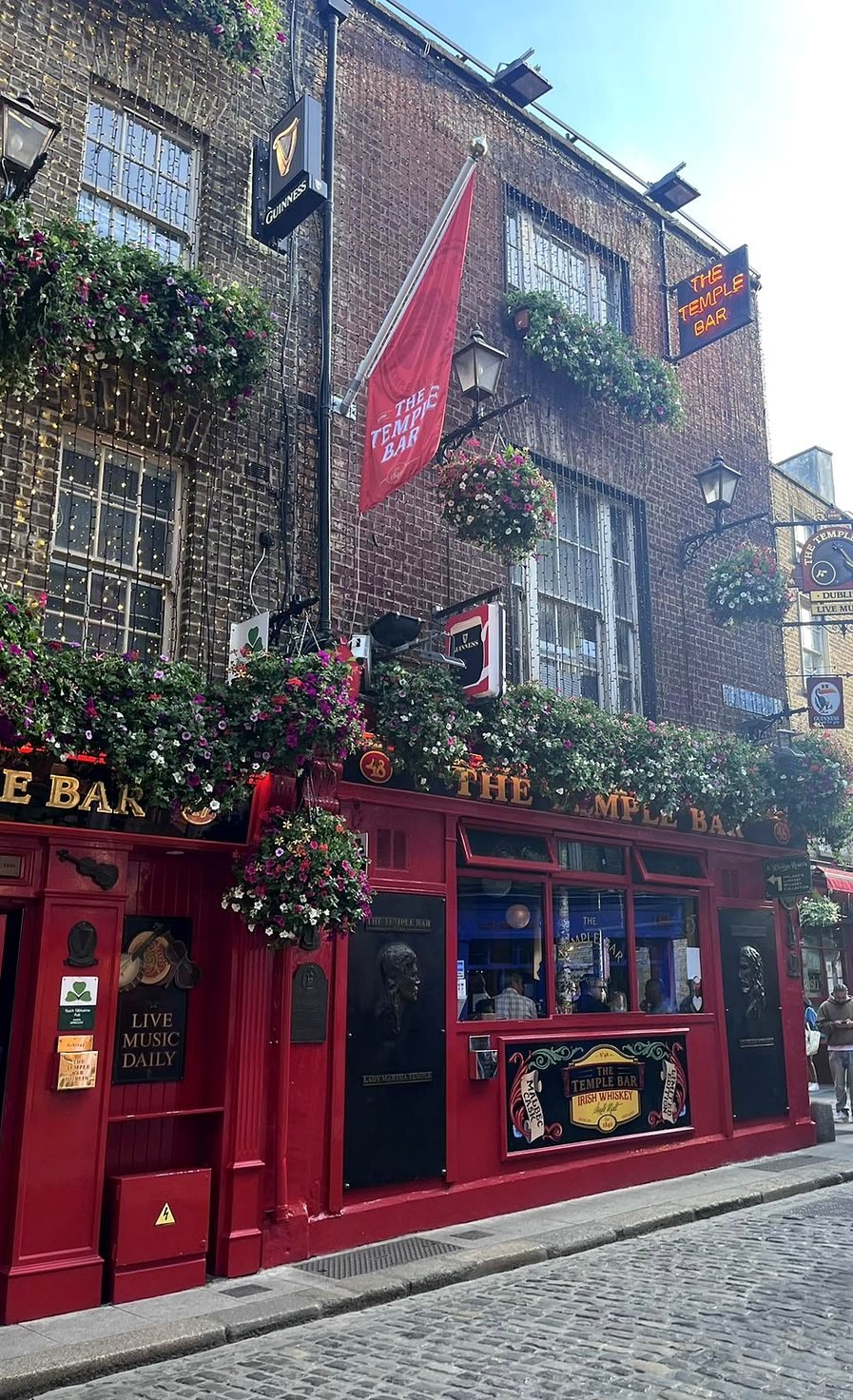 Fachada vermelha florida do pub The Temple Bar em Dublin