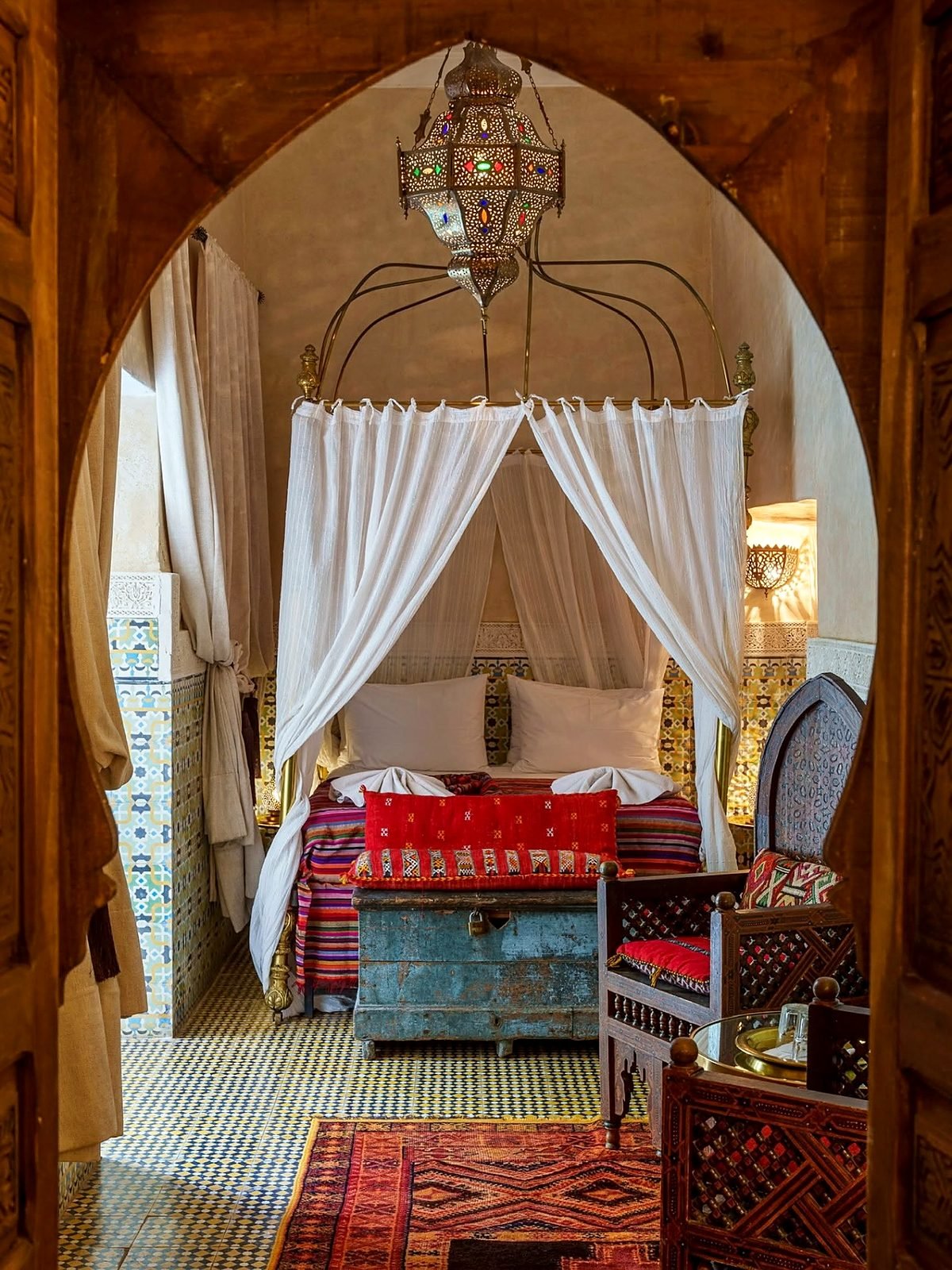 Quarto de riad tradicional marroquino com dossel, luminária de metal e azulejos