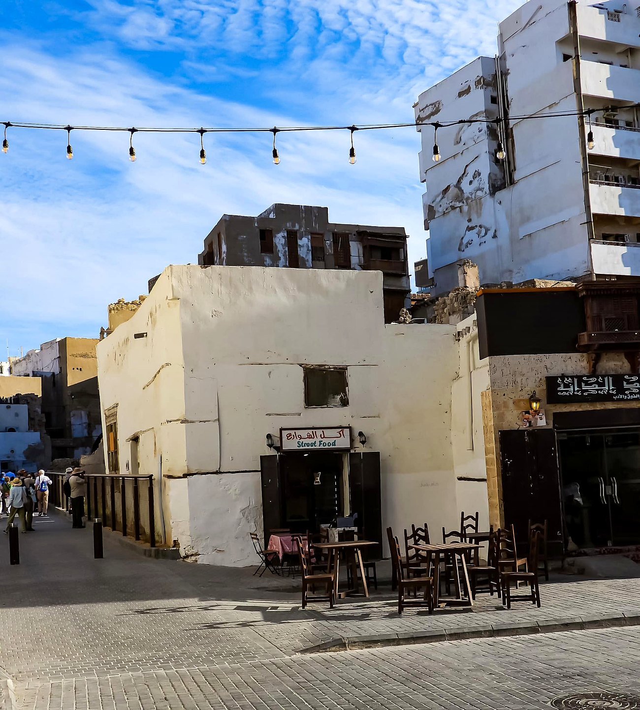 Casa antiga caiada em Al-Balad com mesas de comida de rua na calçada