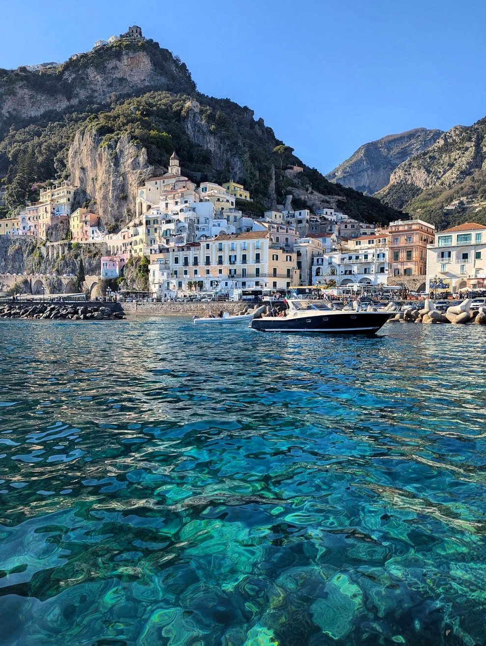 Barco no mar cristalino em frente à cidade de Amalfi