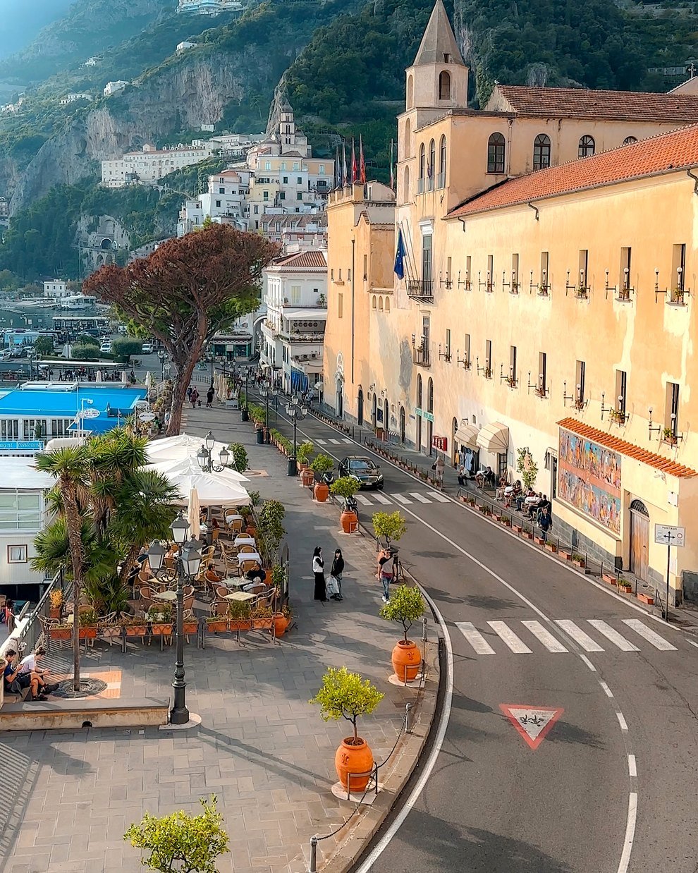 Orla de Amalfi com cafés, vasos de limoeiro e o antigo convento