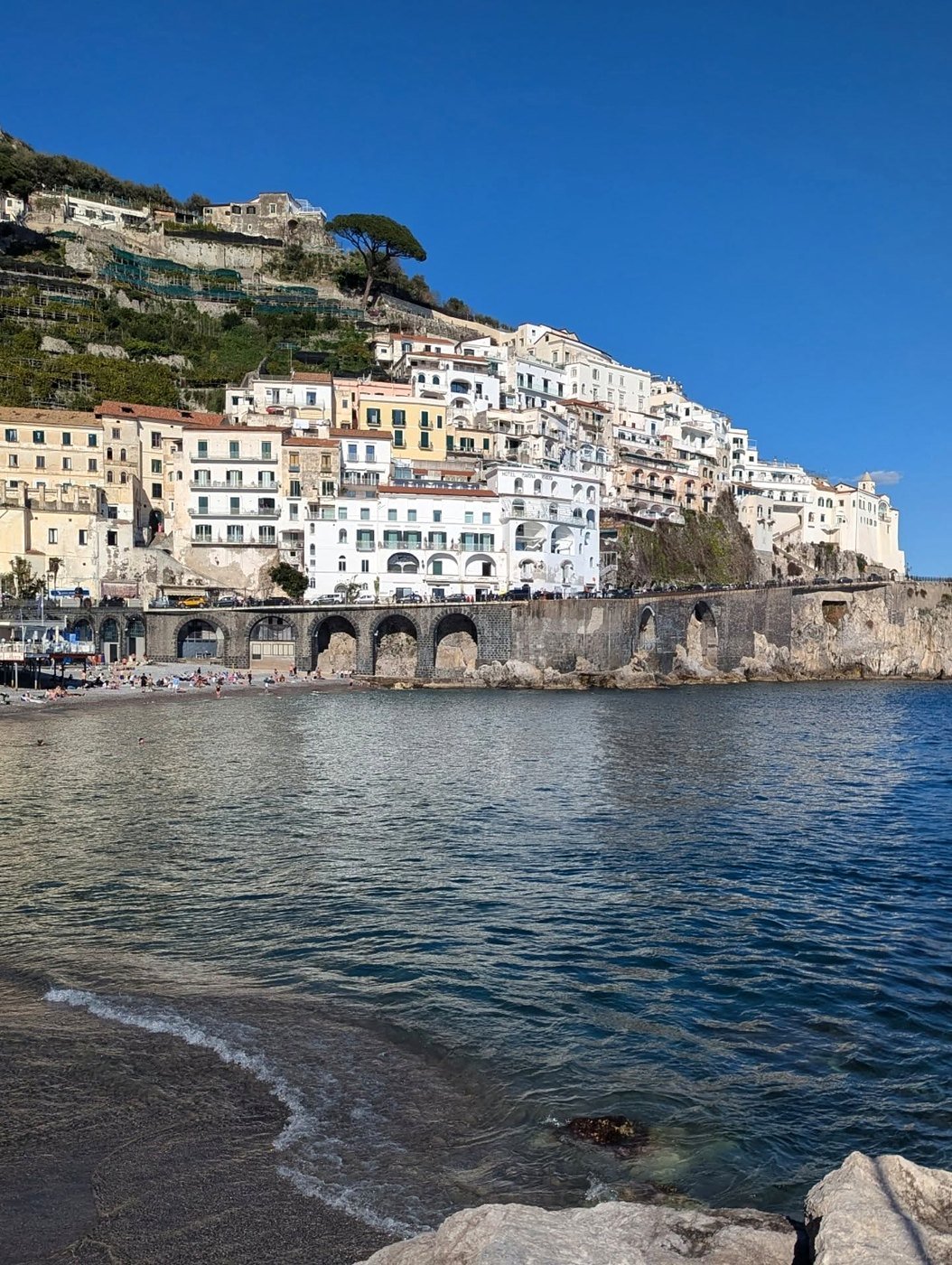 Casas brancas de Amalfi vistas da praia com o mar calmo à frente
