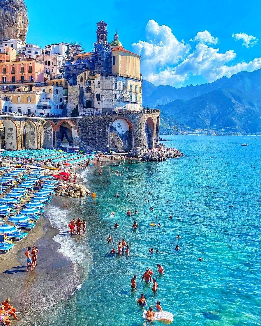 Praia de Atrani com guarda-sóis azuis e mar azul-turquesa
