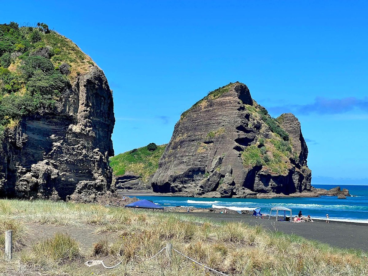 Rochedos e areia preta da praia de Piha, na costa oeste de Auckland