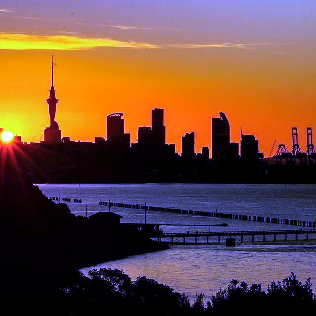 Silhueta da Sky Tower e dos prédios de Auckland ao pôr do sol