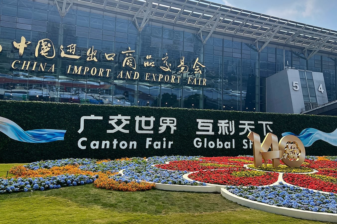 Fachada do complexo da Canton Fair em Guangzhou, com o jardim de flores e o letreiro da feira