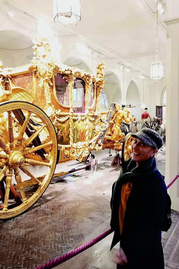 Rita Castelan, guia brasileira em Londres, ao lado de uma carruagem real dourada