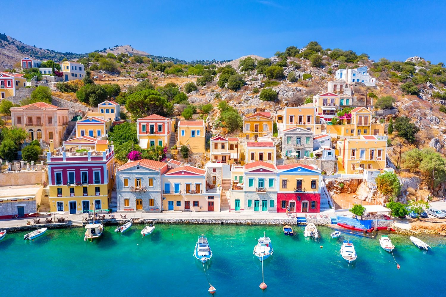 Casas neoclássicas coloridas à beira da água no porto da ilha de Symi, passeio de barco saindo de Rodes
