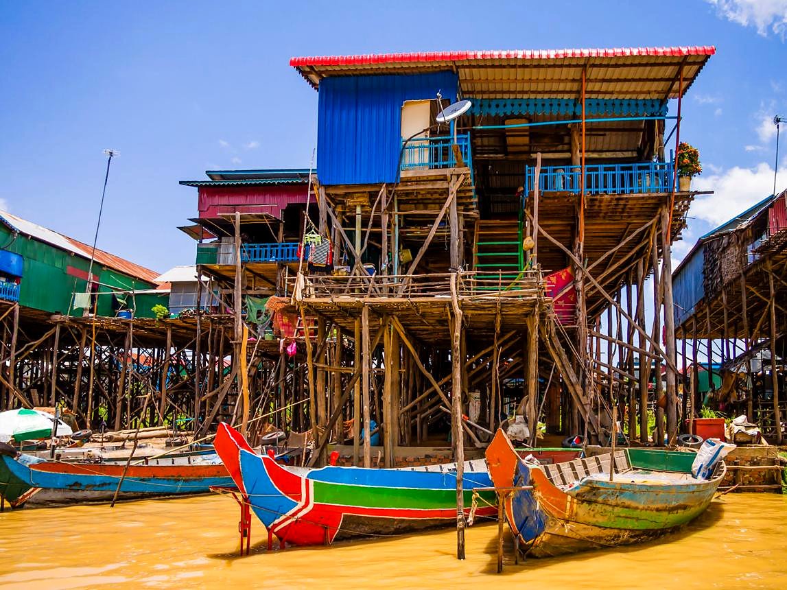 Casa de palafita com barcos coloridos no lago Tonlé Sap, Camboja