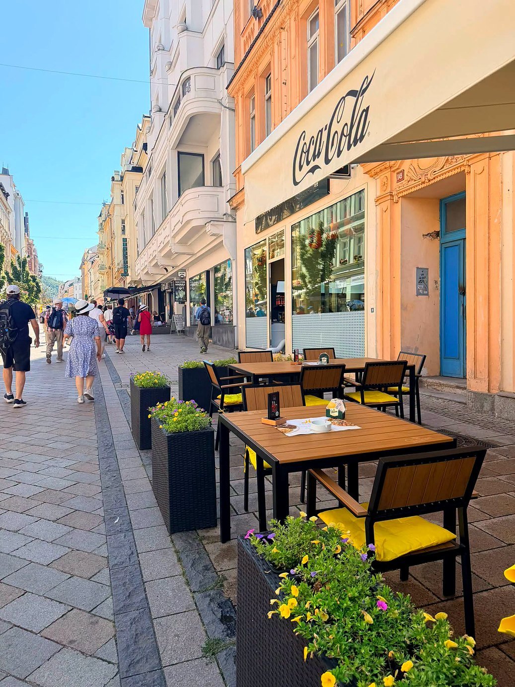 Calçadão de pedra com mesas de café ao ar livre e prédios históricos em Karlovy Vary