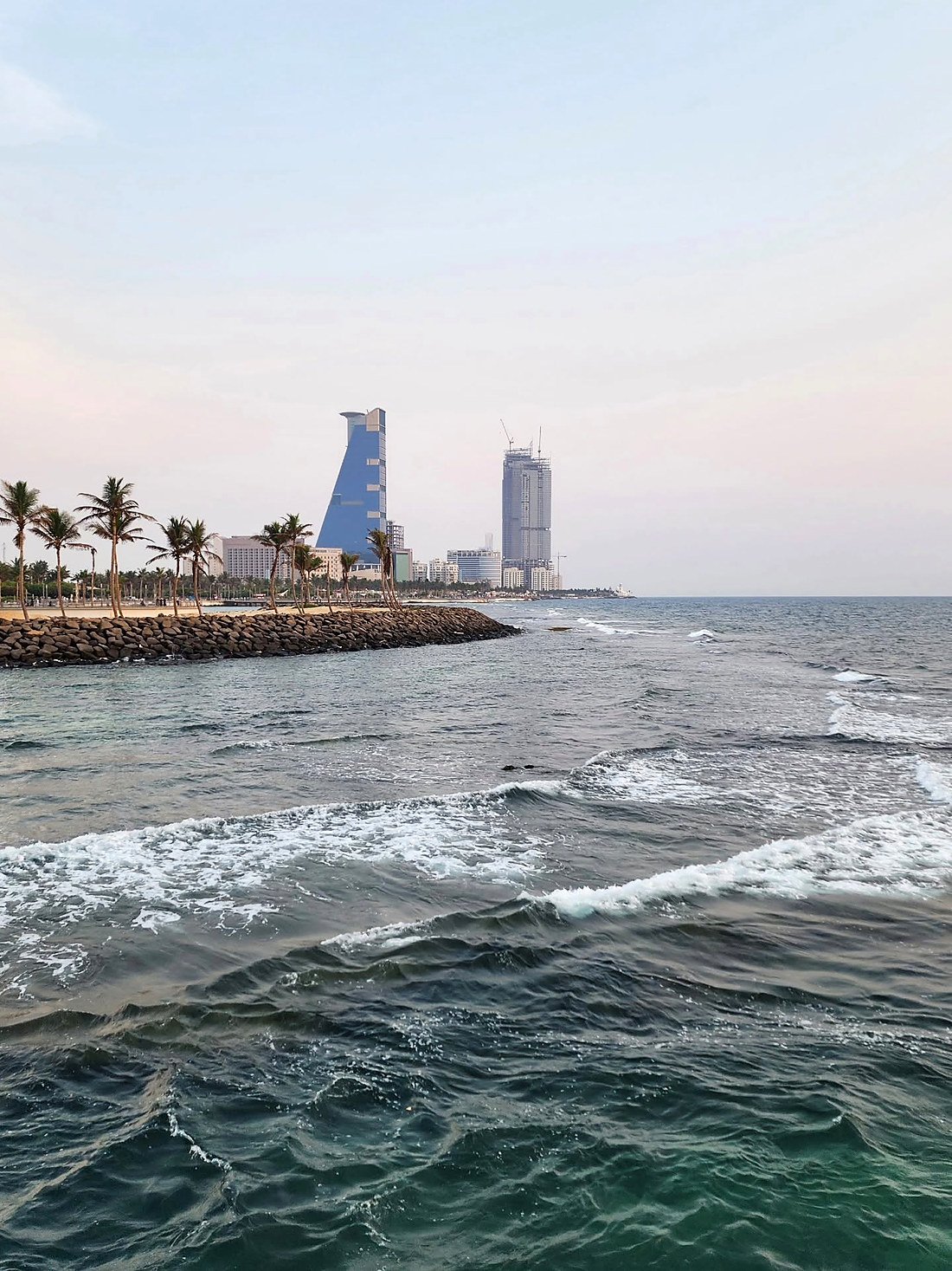 Corniche de Jeddah com coqueiros, quebra-mar e prédios modernos ao fundo