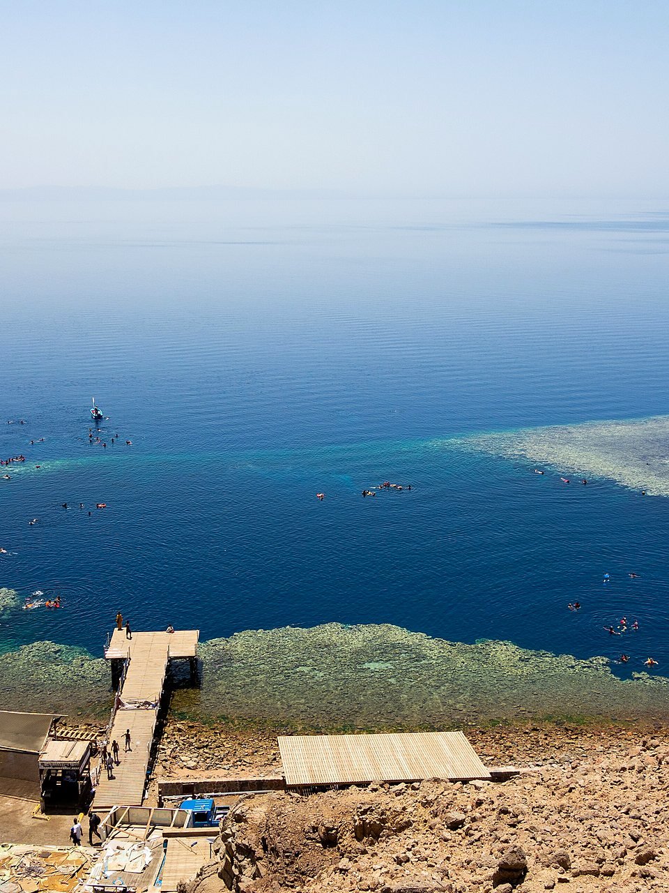 Blue Hole de Dahab visto do alto, com píer e pessoas fazendo snorkel na borda do recife