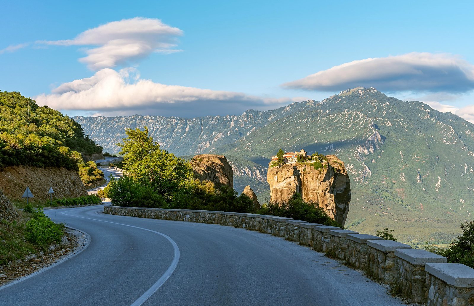 Estrada sinuosa chegando a Meteora com o Mosteiro da Santíssima Trindade no alto do rochedo, no caminho do transfer de Atenas