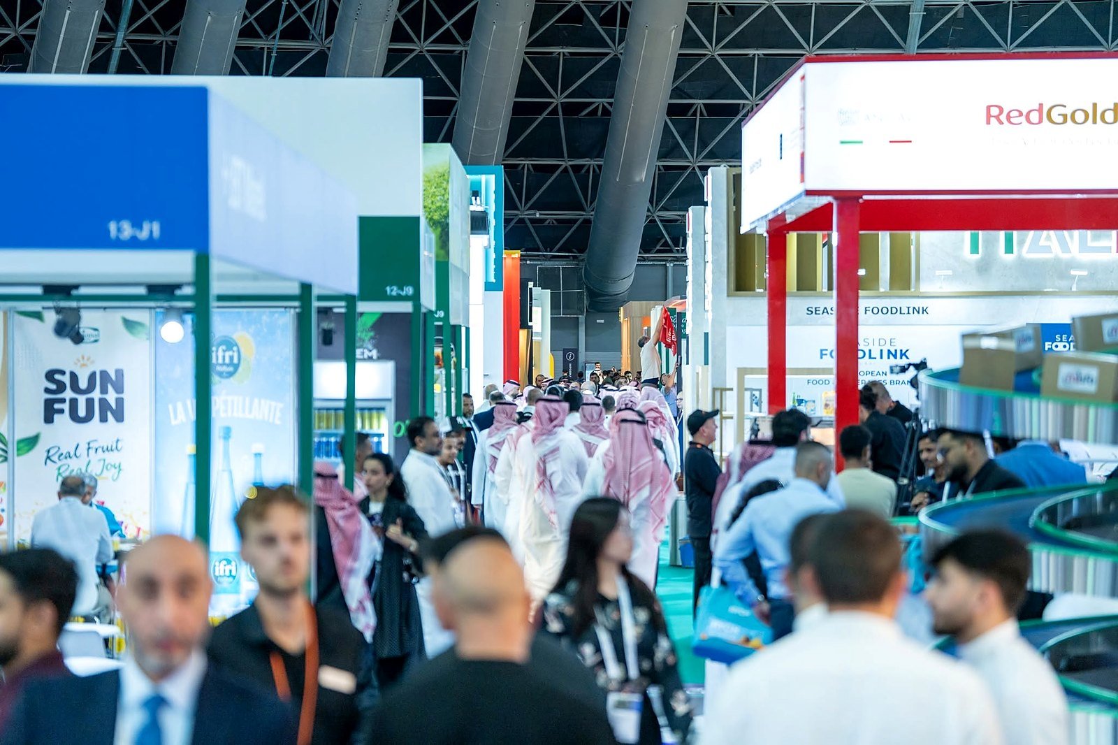 Corredor movimentado de feira de alimentos em Jeddah com estandes e visitantes