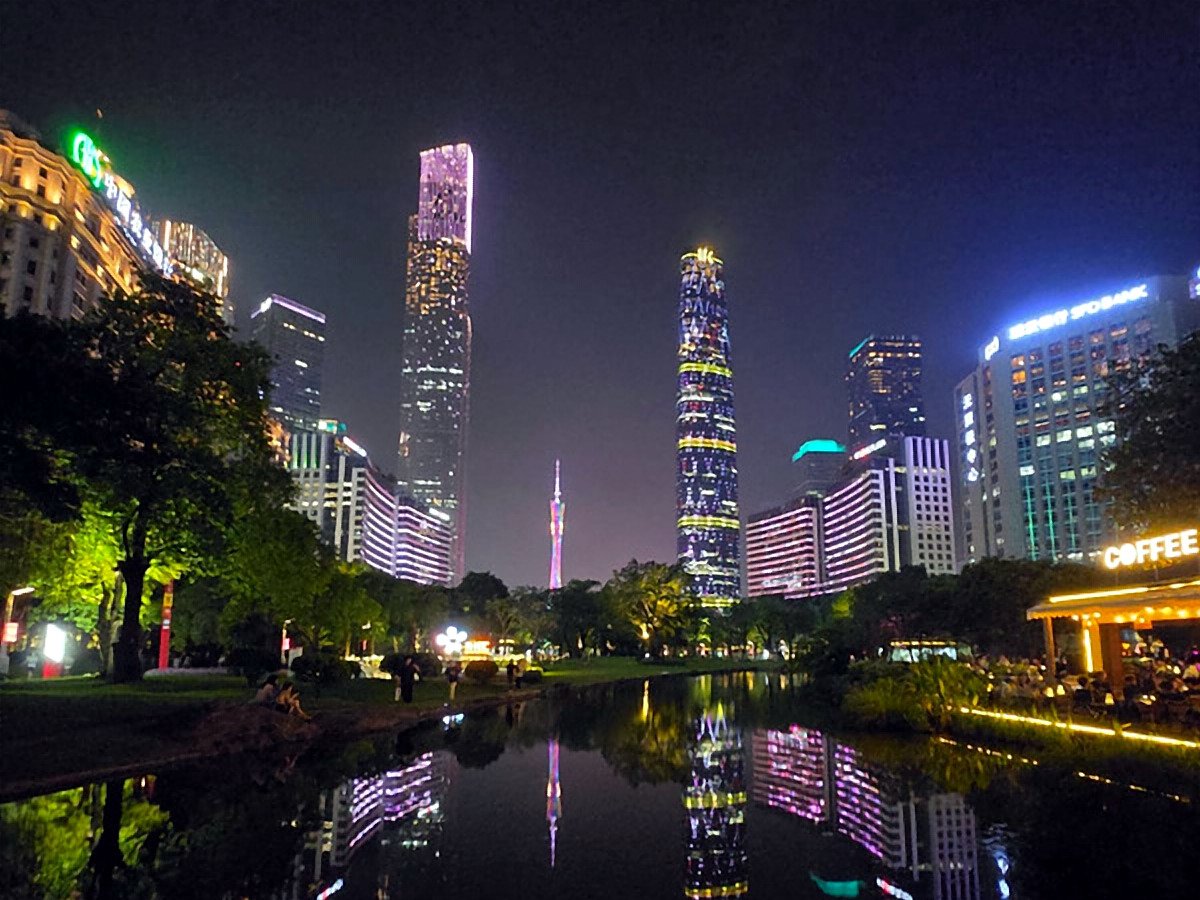 Guangzhou à noite, com a Canton Tower e os arranha-céus refletidos no lago