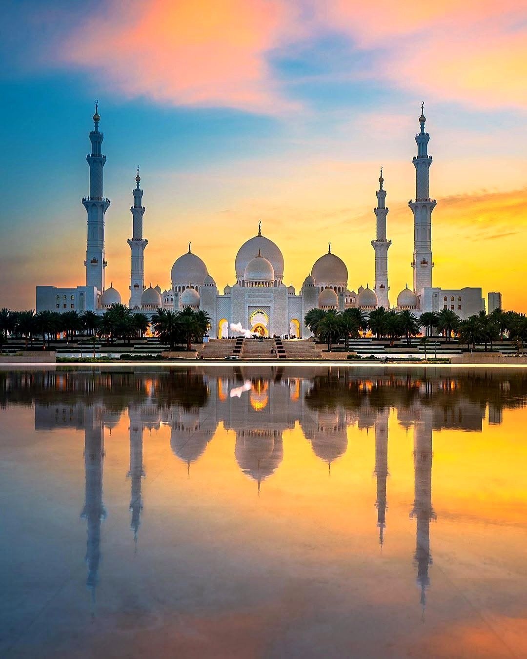 Grande Mesquita Sheikh Zayed refletida no espelho d'água ao entardecer