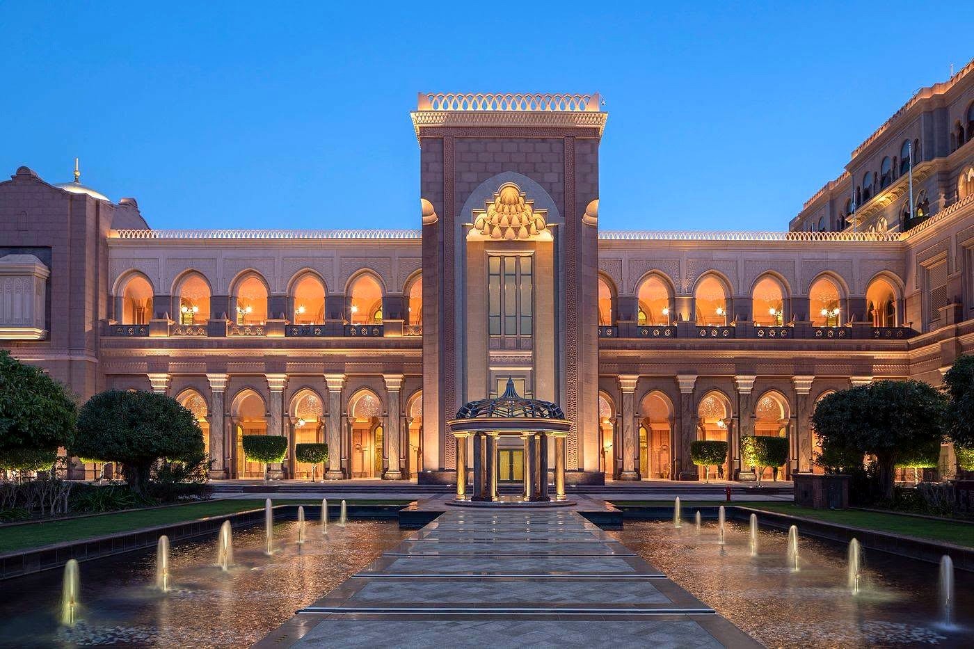 Fachada iluminada do Emirates Palace com fontes nos jardins em Abu Dhabi