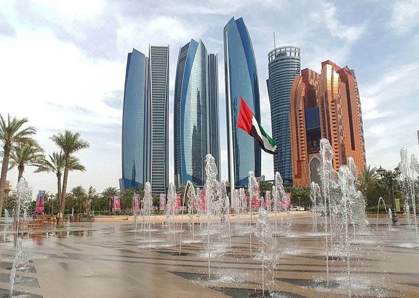 Etihad Towers e bandeira dos Emirados Árabes vistas da praça de fontes