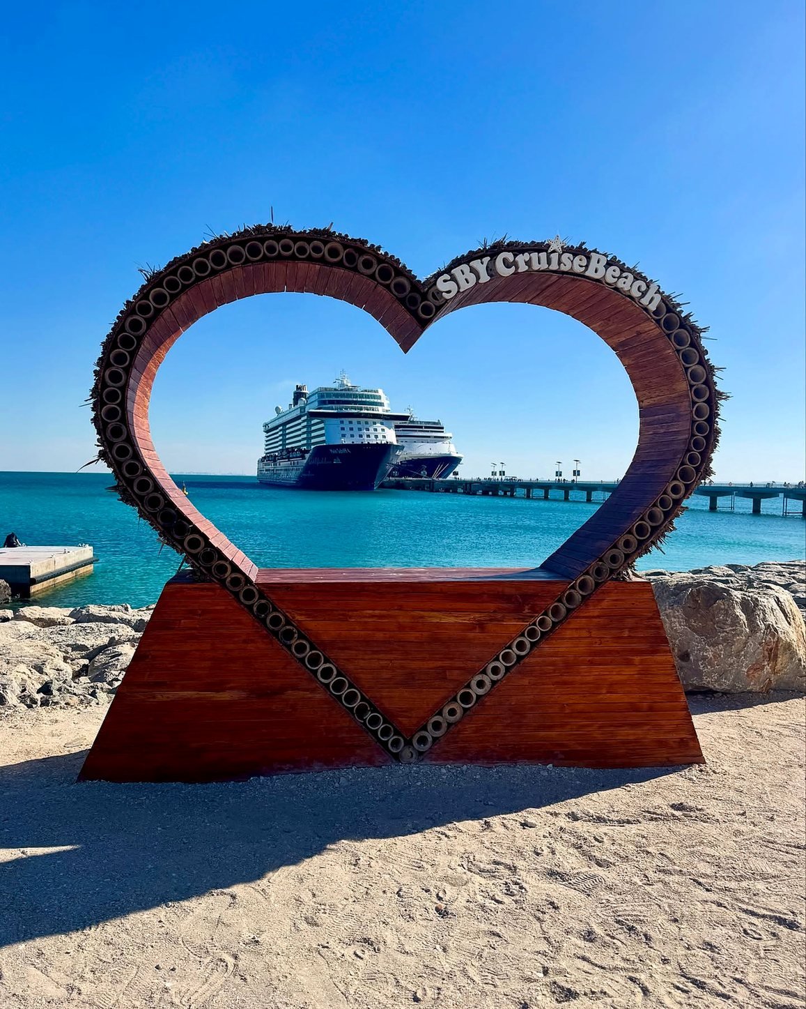 Navios de cruzeiro vistos pela moldura de coração na praia da ilha Sir Bani Yas