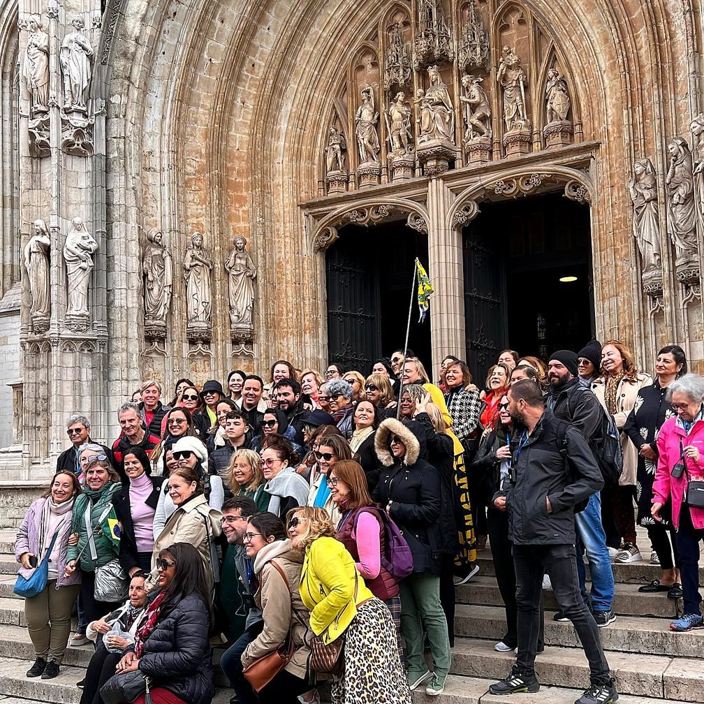 Grande grupo de viajantes brasileiros reunido com a Graça na escadaria de uma catedral gótica na Bélgica