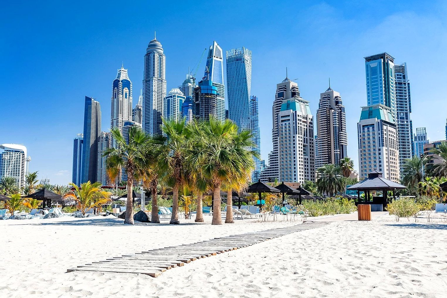 Praia de JBR com palmeiras e os arranha-céus da Dubai Marina